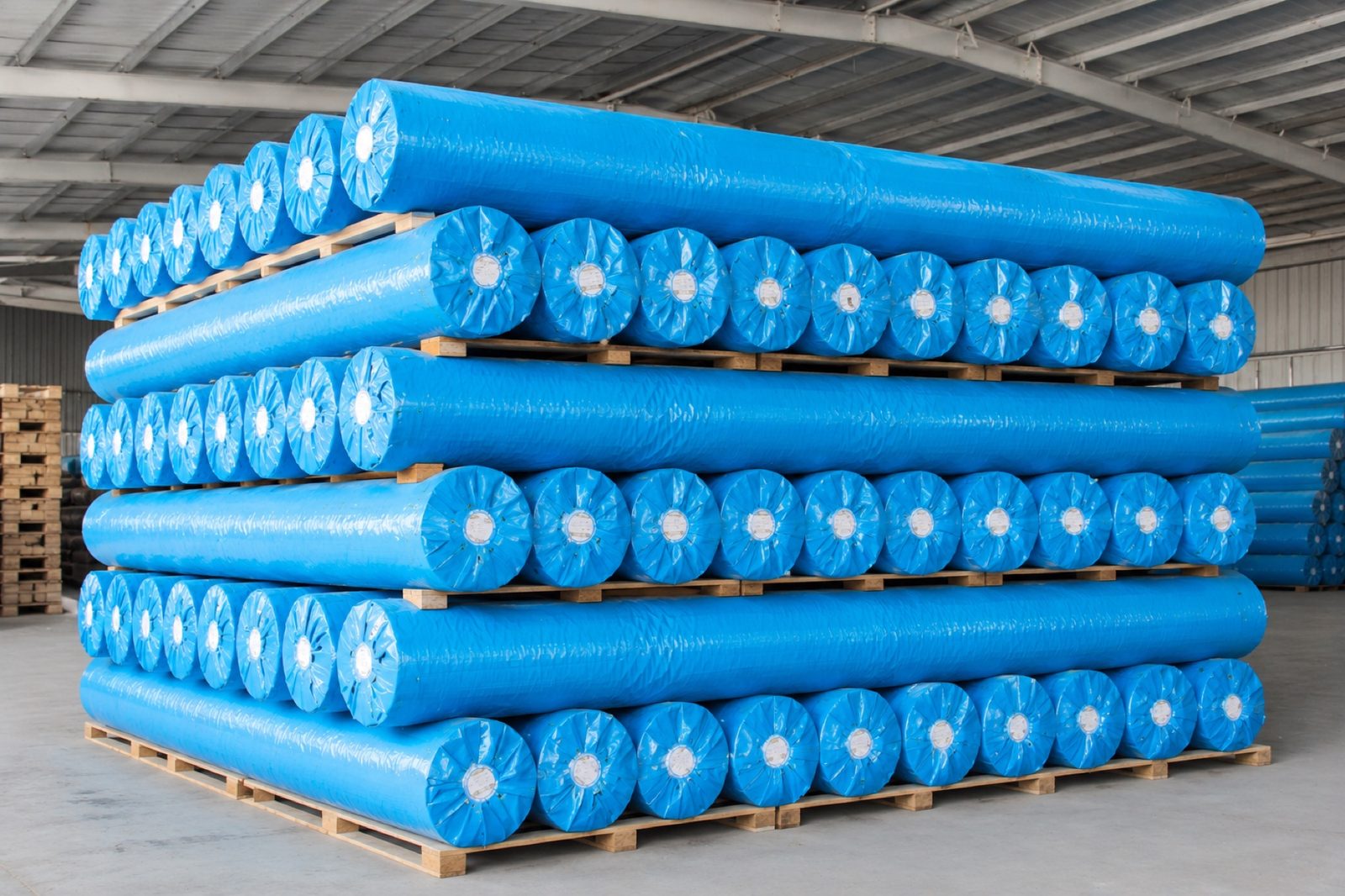 Finished agricultural fabric rolls packed and stacked in factory warehouse